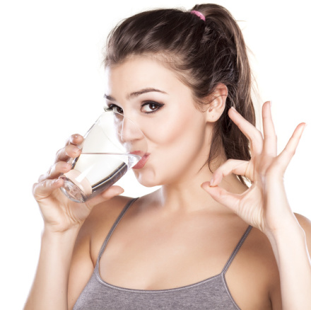 beautiful woman drinks water from a glass and shows delicious